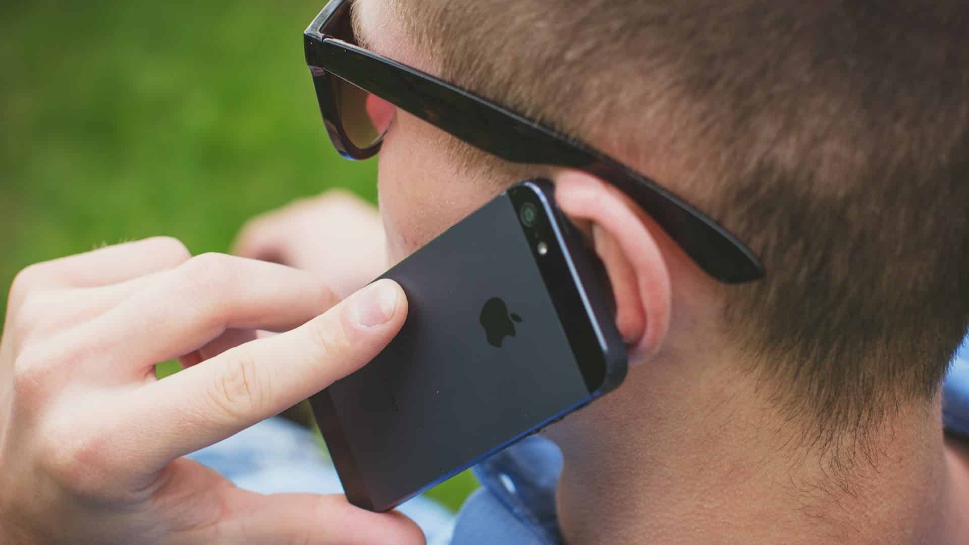 Gros plan : un homme porte son smartphone à son oreille pour téléphoner.