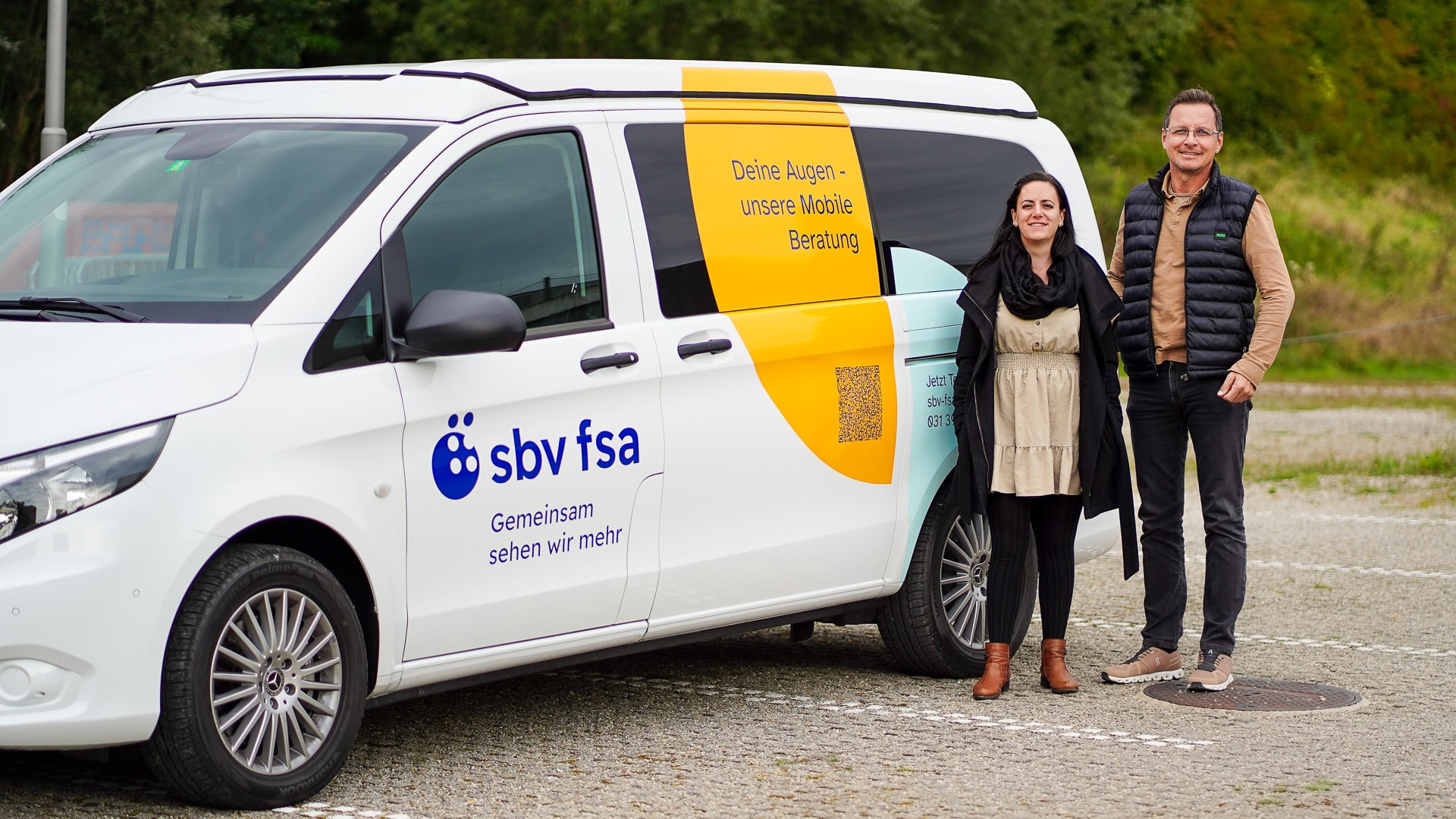 Bus (links) und 2-köpfiges Team (rechts) der Mobilen Beratung. Der Bus ist weiss, mit sbv-fsa-Logo und farbigen Halbkreisen mit Beschriftungen versehen.