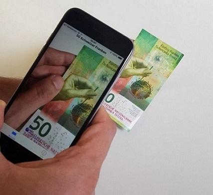 Eine Hand hält ein Smartphone, das via App die Note erkennt.