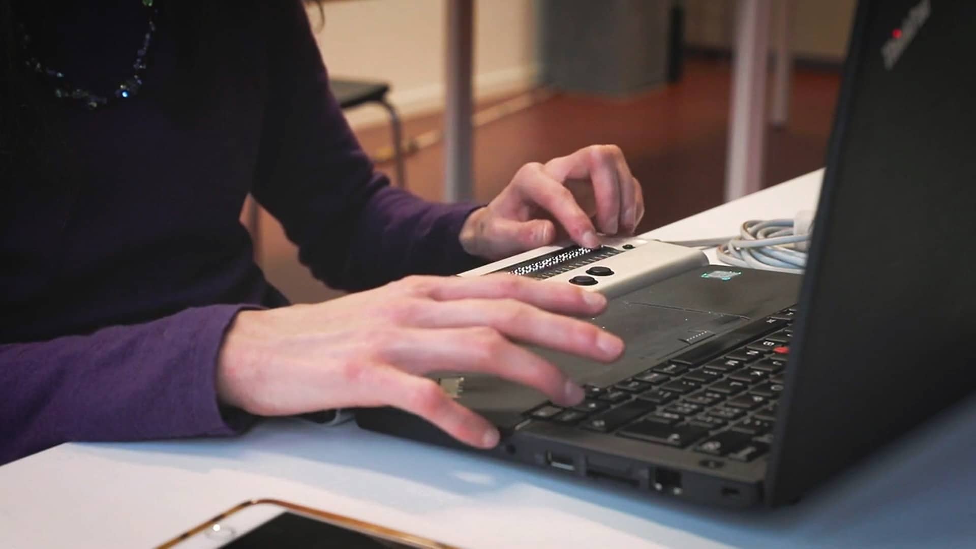 Gros plan: une femme utilise avec ses mains un ordinateur portable équipé d'une ligne braille.