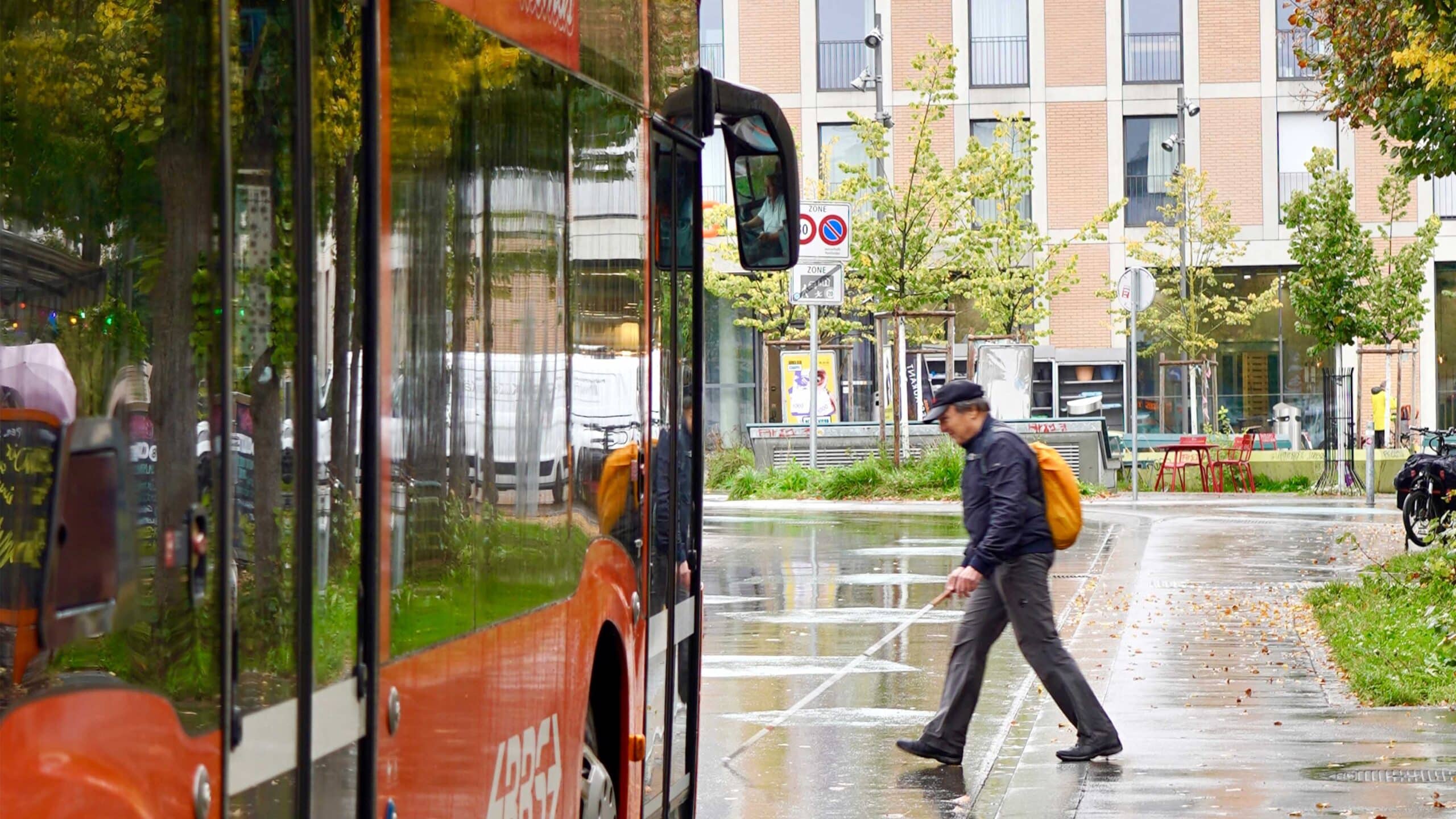 Eine sehbehinderte Person überquert die Strasse vor einem Bus.