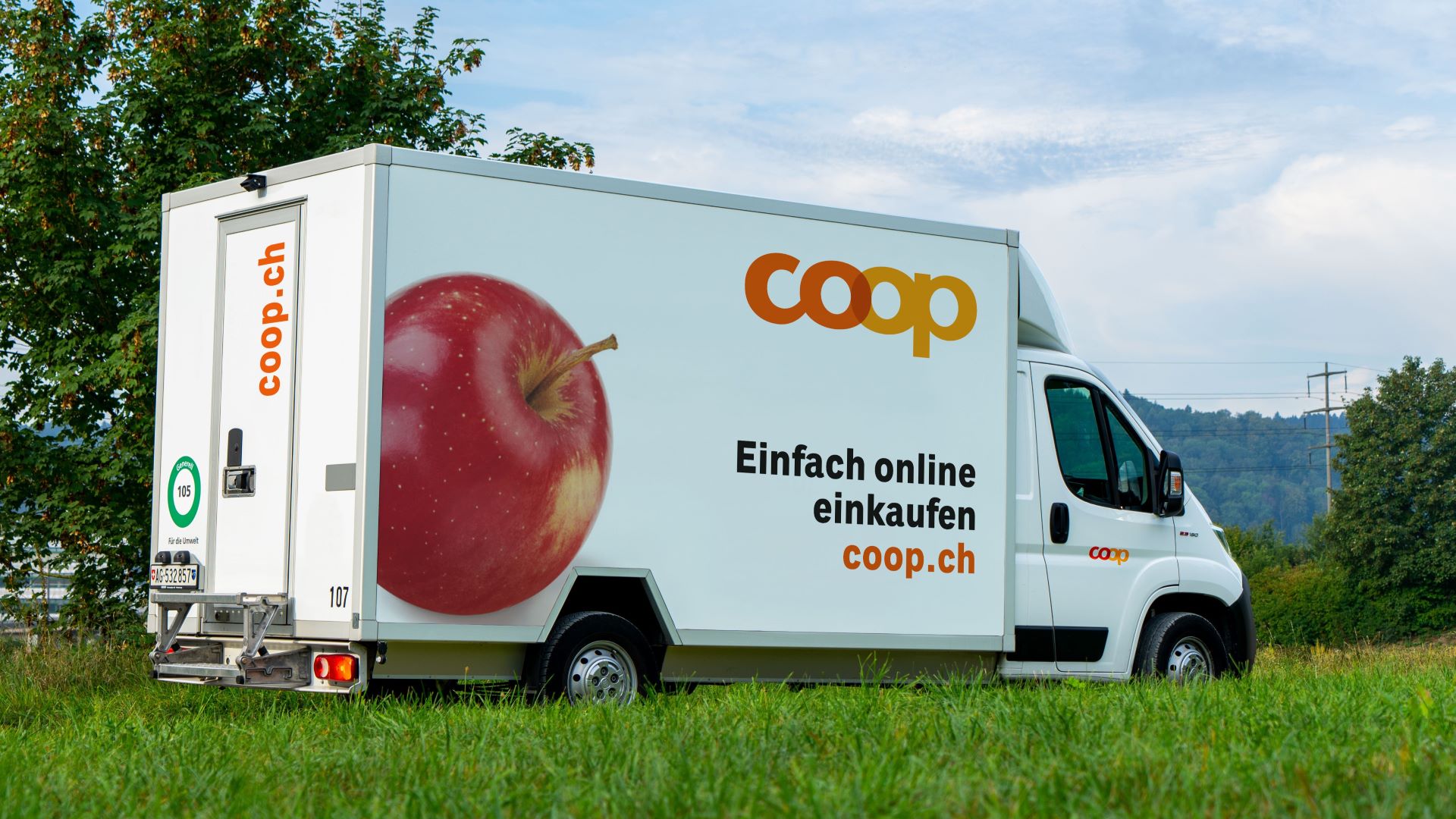 Ein weisser Coop-Lieferwagen fährt durch die Landschaft. Auf dem Lieferwagen steht: 