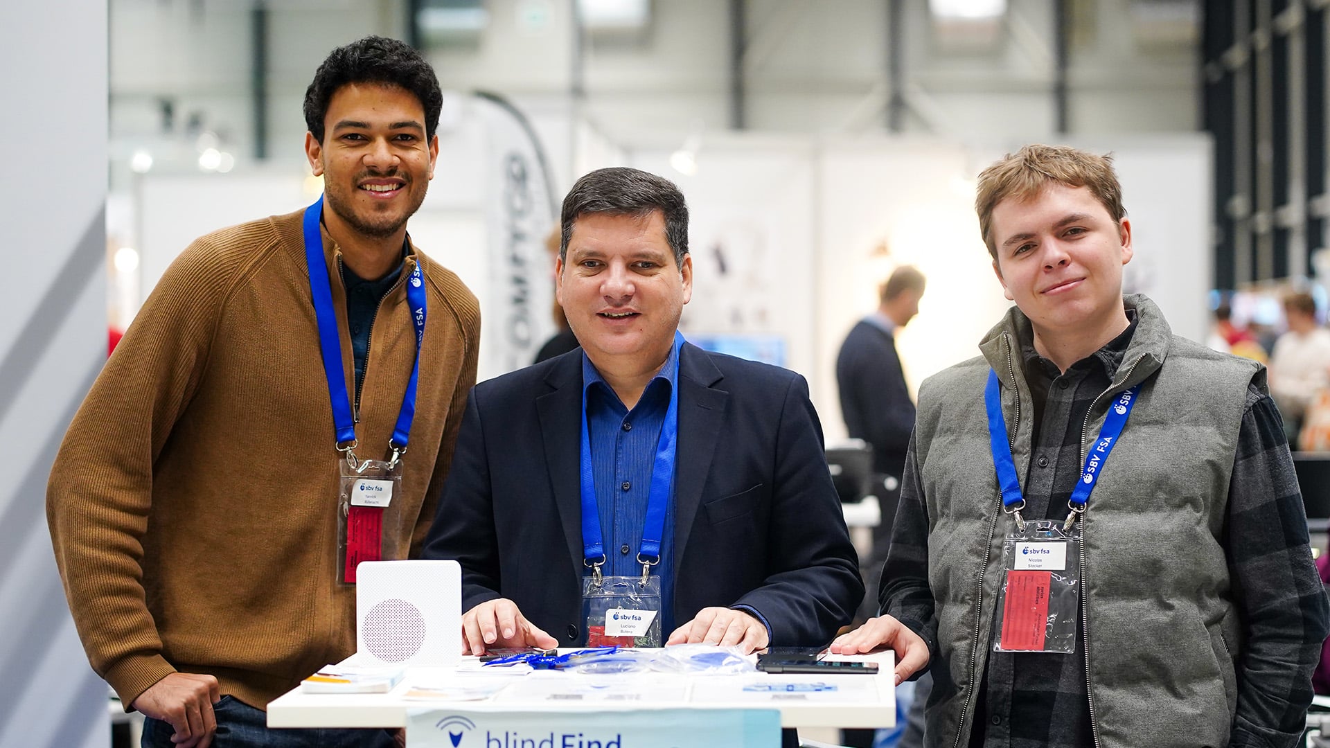 Les collaborateurs de l'asbl se tiennent ensemble sur le stand et regardent la caméra avec bonheur.