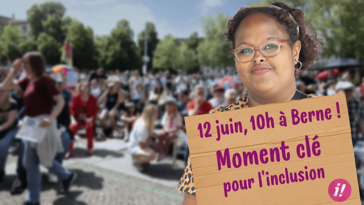 À l’arrière-plan, une foule dense et indistincte est rassemblée pour une manifestation. À l’avant, sur la droite de l’image, une femme tient une pancarte en carton. Sur celle-ci, on peut lire, inscrit en lettres roses: 12 juin à 10h à Berne: Moment clé pour l’inclusion