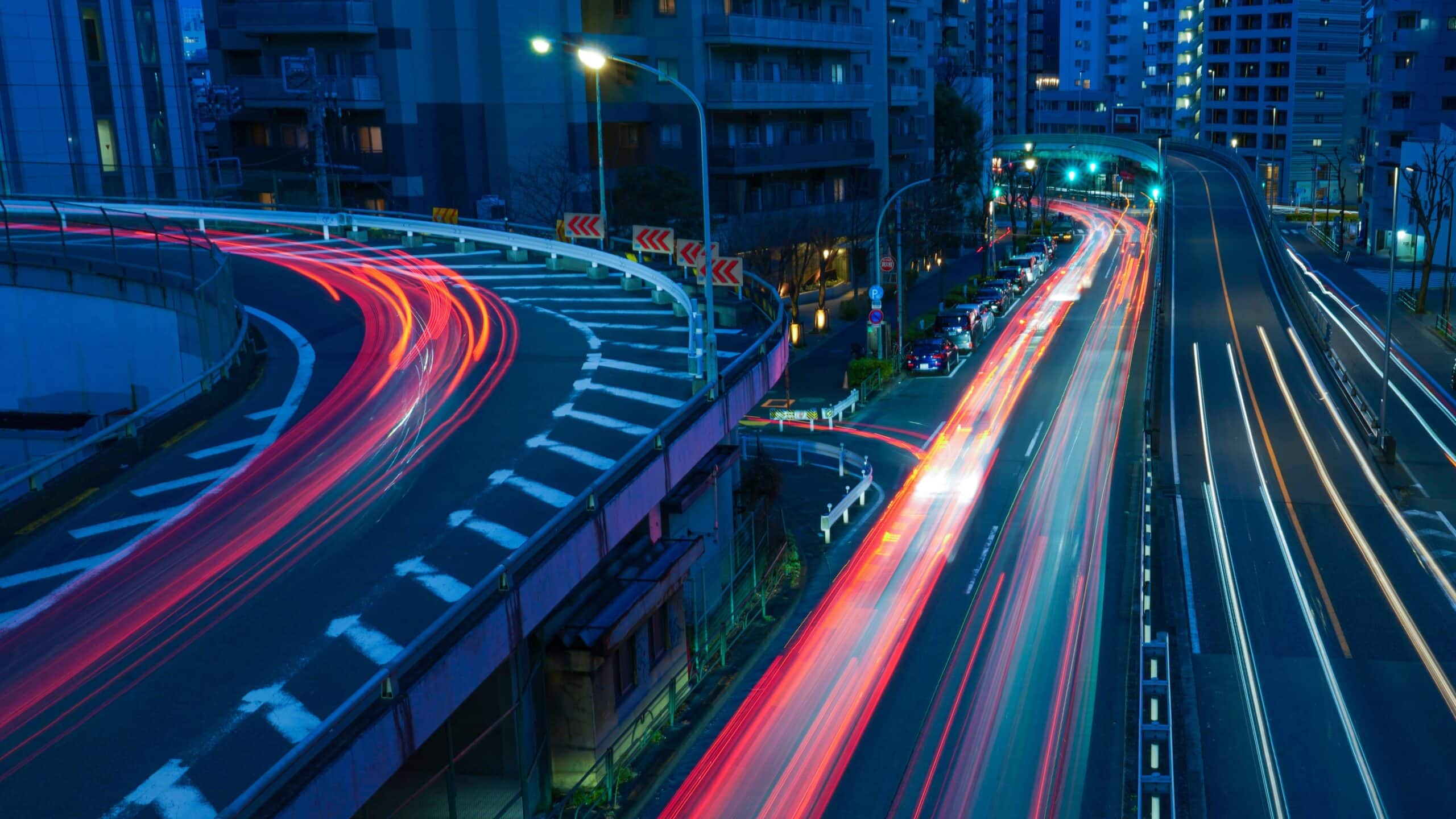 Rue au crépuscule, la photo est longuement exposée, on voit les voitures qui passent comme une « traînée de lumière ».