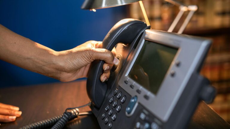 Festnetztelefon, eine Hand greift nach dem Hörer