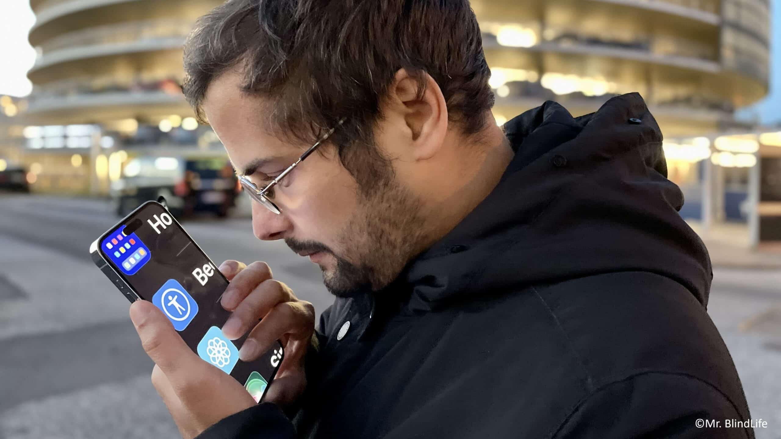 Ein Mann mit Brille ist von der Seite fotografiert und schaut auf sein Smartphone.