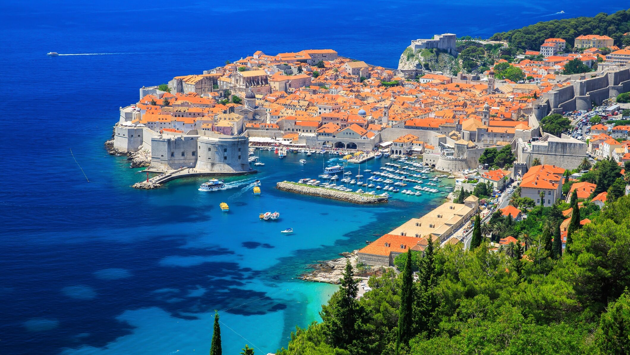 Un village aux toits orange surplombant la mer, entouré d'une eau bleue cristalline.