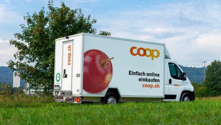 Weisse Lieferwagen von Coop in einer grünen Landschaft. Darauf steht: Einfach online einkaufen coop.ch