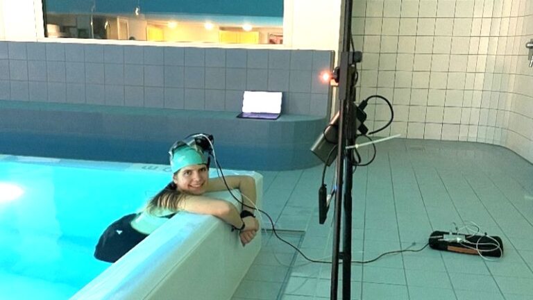 Femme dans une piscine intérieure au bord de la piscine, rougeur avec des câbles sur la tête.
