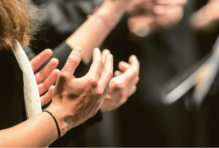 Les mains expressives de choristes en pleine performance, capturent l’émotion et la passion du chant