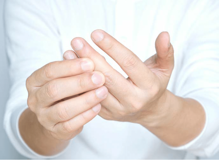 Une personne masse un doigt de sa main avec l’autre main, probablement pour soulager une douleur ou pratiquer un auto-massage thérapeutique.