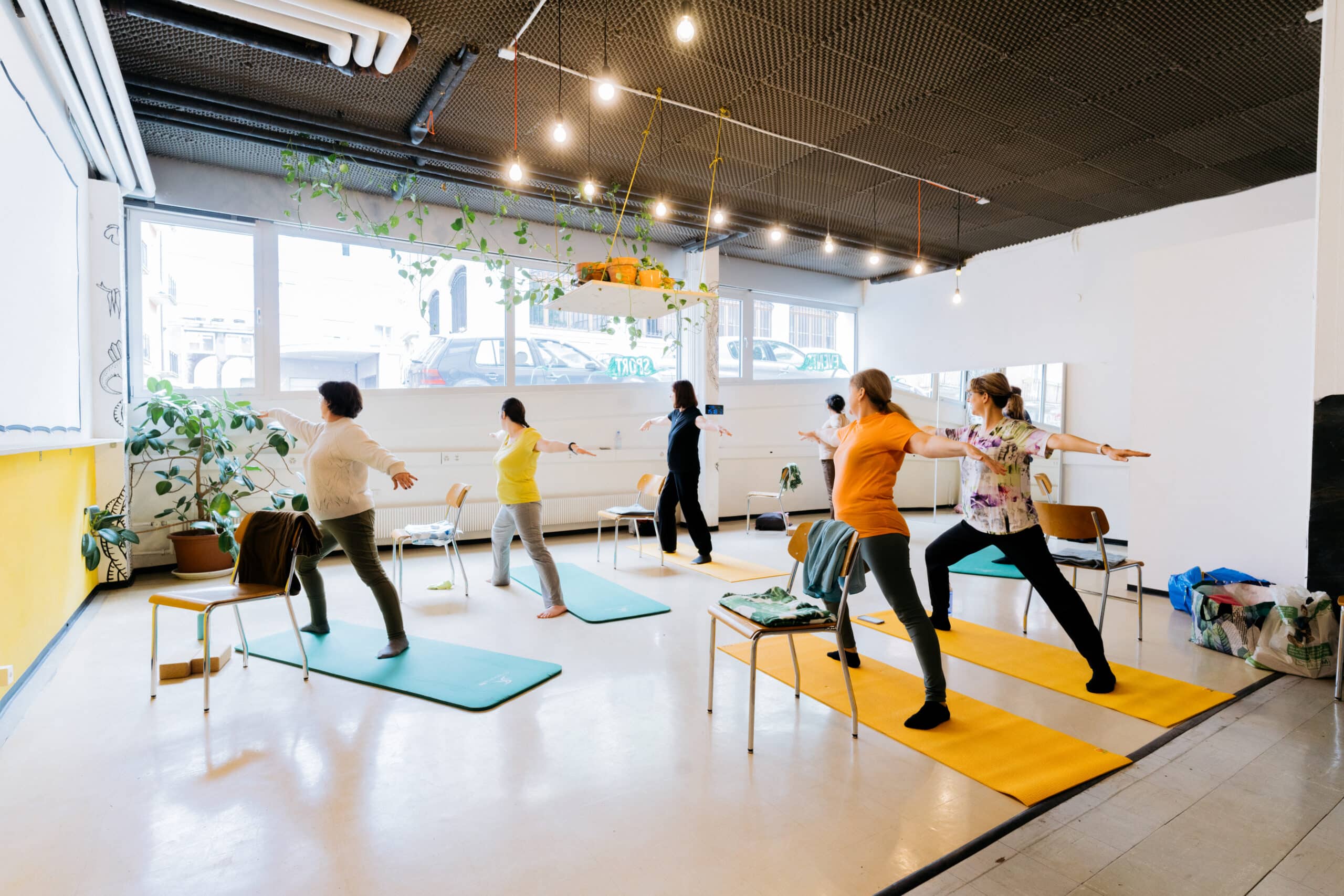 6 participants dans une salle de yoga, position du deuxième guerrier. Photo de Tyler Merkel