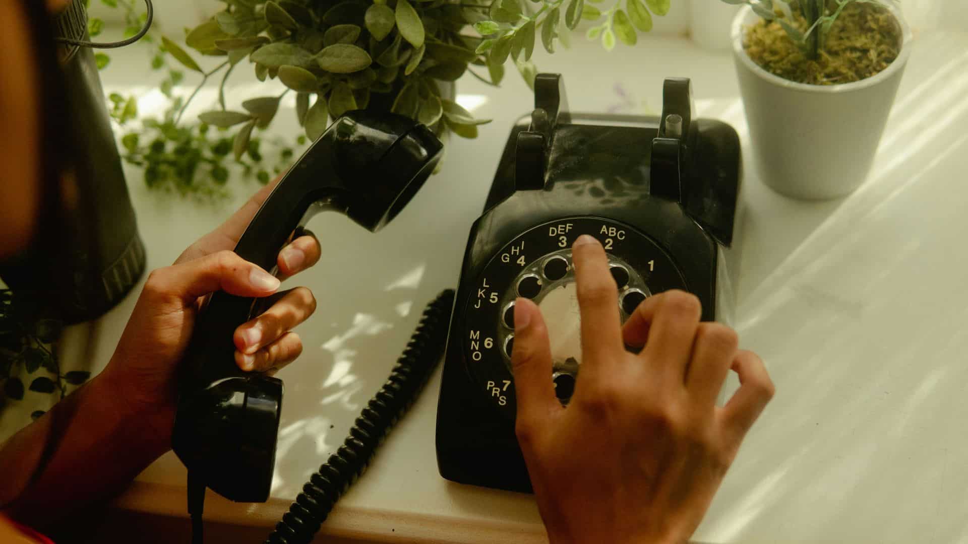 Ancien téléphone à cadran, la main compose le numéro