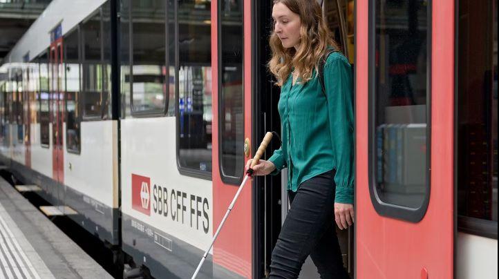 Une femme avec canne blanche qui descend du train.