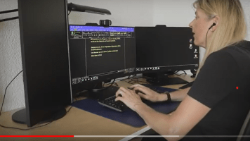 Ausschnitt aus einem Video, das im Kurs "Videobewerbung" entstanden ist:  Eine blonde Frau sitzt an einem PC und hat Kopfhörer auf, auf dem Bildschirm erkennt man einen schwarzen Hintergrund mit gelbem Text 