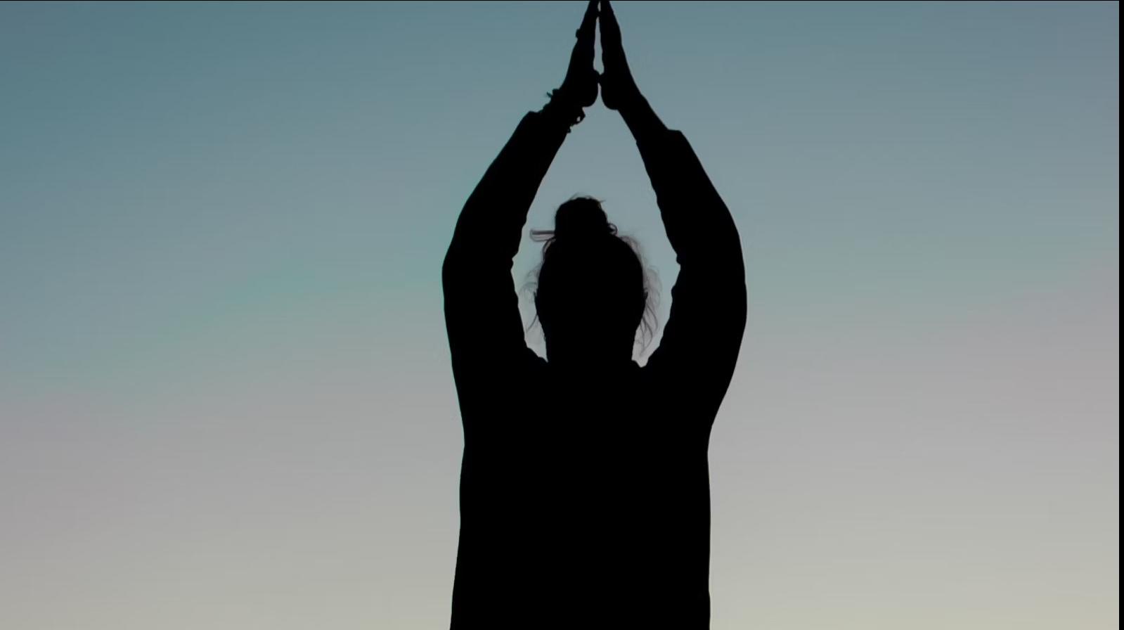 Silhouette d’une personne en position de yoga, vue à contre-jour