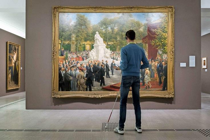 Person mit Langstock steht vor einem grossen Wandbild (Foto- Harry Schnitger Berlinische Galerie)